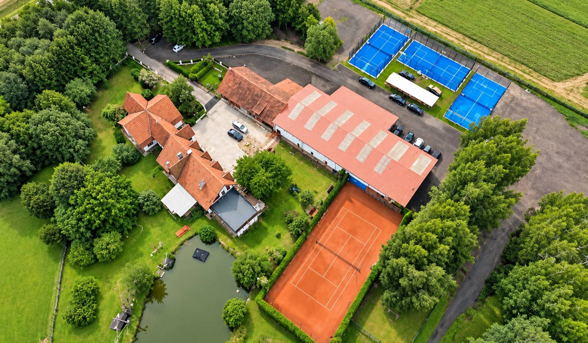 Tennis1 aikštynas iš oro: pastatas su vidaus kortu, lauko molio kortas ir trys mėlyni padelio kortai
